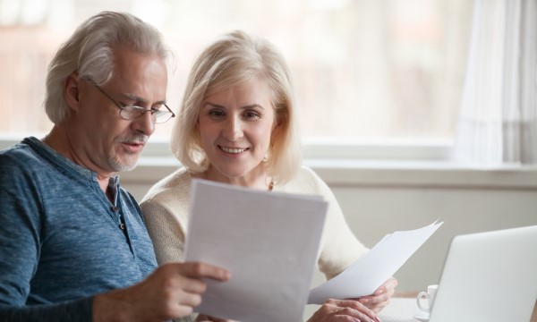 Poll: Americans Display Concern, Optimism With Financial Well-Being: Older couple pleased with paperwork using laptop