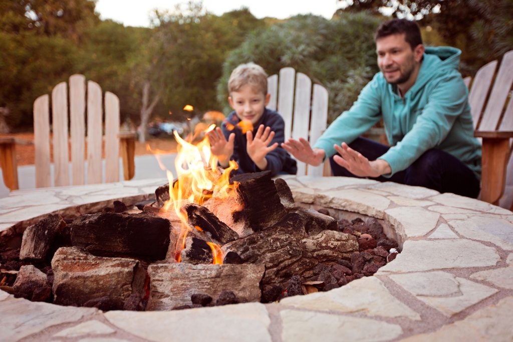 Your Central Oregon Home Loan Provider | view of firepit and happy smiling family of two, father and son, warming their hands by the fire and enjoying time together in the background